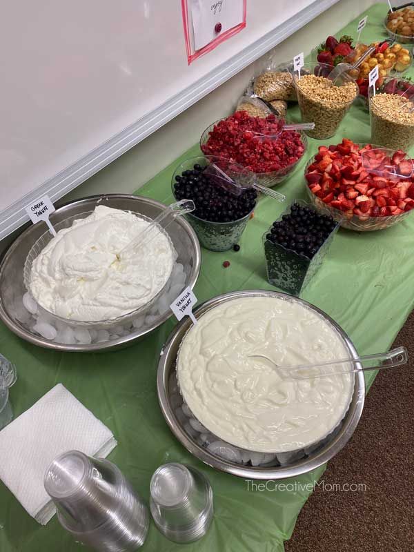 an assortment of desserts are on display at a buffet table with green cloth and white napkins