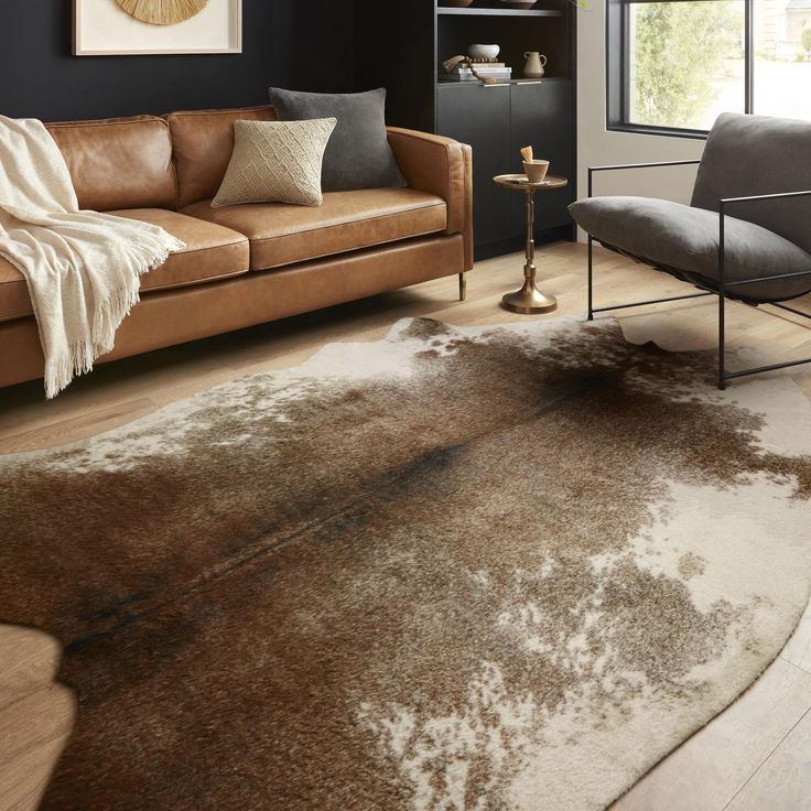 a living room filled with furniture and a brown rug on top of a hard wood floor