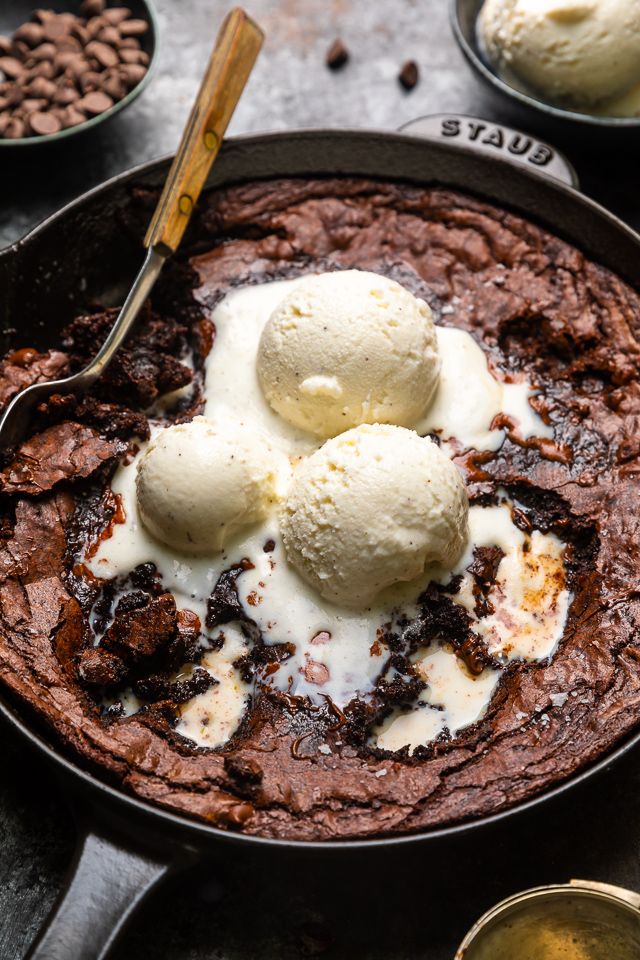 two scoops of ice cream sit in a skillet with chocolate pudding and coffee beans