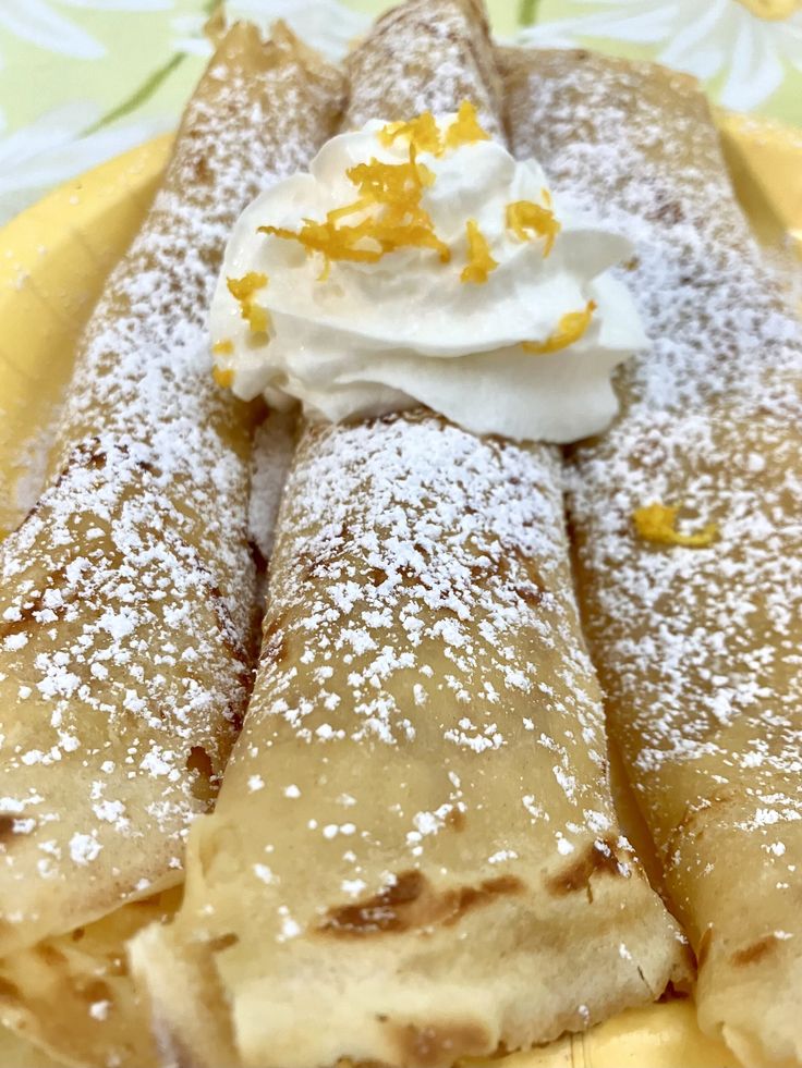 a plate topped with crepes covered in powdered sugar