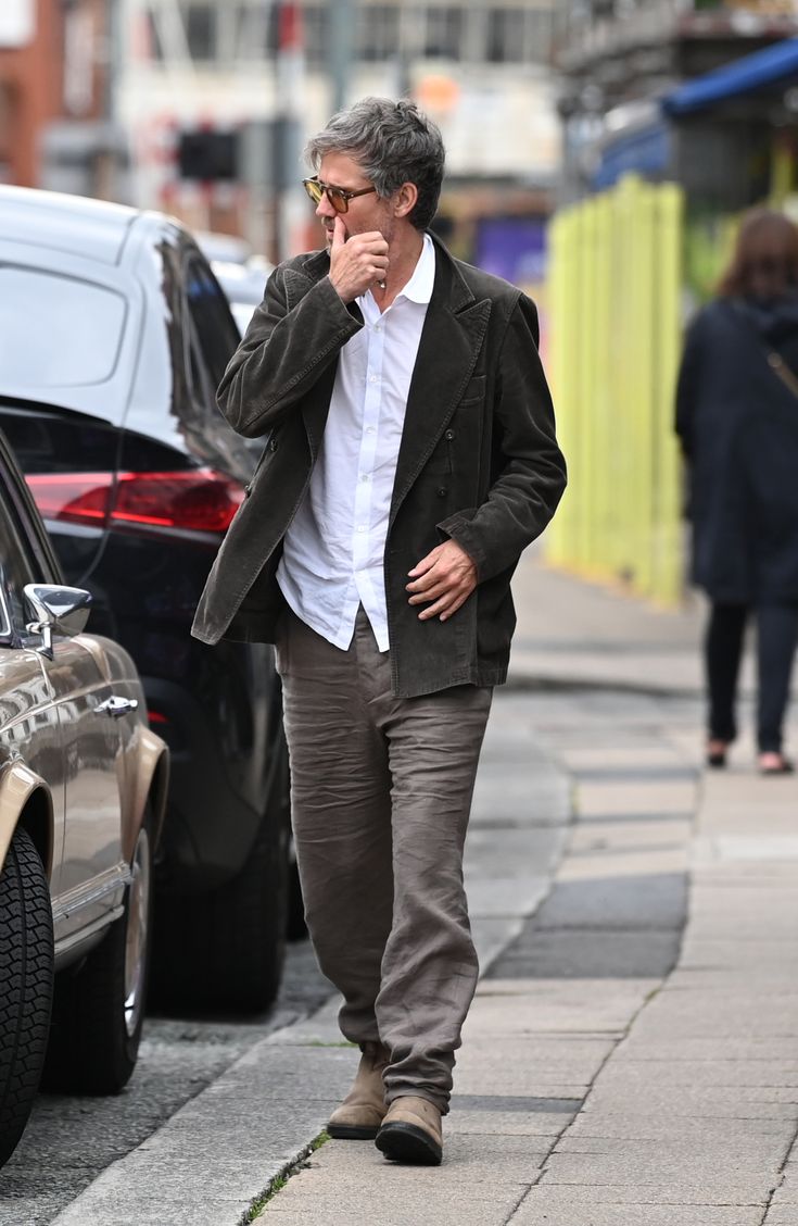 a man is walking down the street talking on his cell phone while holding his hand to his face