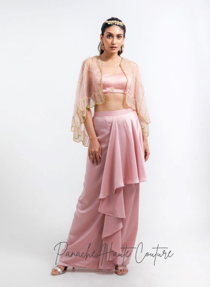 Introducing our stunning Dhoti skirt set, perfect for any special occasion! The skirt is made from luxurious satin fabric, which drapes beautifully and feels incredibly comfortable against the skin. The skirt features a unique dhoti style, which adds a touch of elegance and sophistication to the overall look. The bralette blouse is also made from the same lustrous satin fabric and features a flattering design that accentuates the shoulders and neckline. The combination of the dhoti skirt and bra Dhoti Skirt, Indowestern Gowns, Western Gowns, Reception Gowns, Indo Western Gown, Dusty Pink Color, Indian Fashion Trends, Curated Outfit, Saree Gown