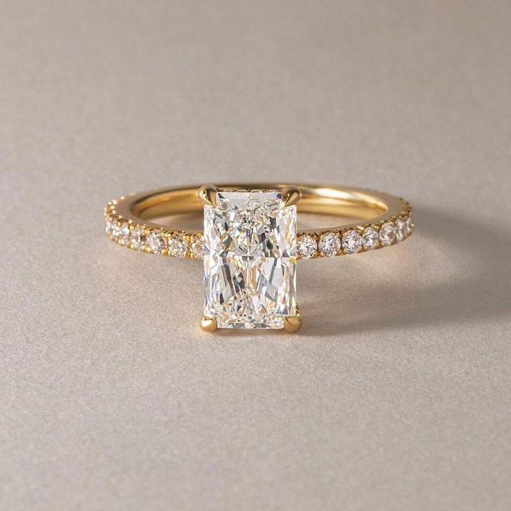 an engagement ring with a princess cut diamond and pave set diamonds on the sides