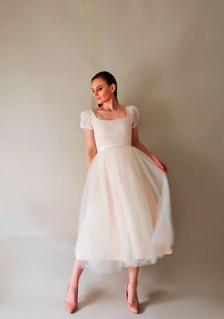 a woman in a white dress posing for the camera with her hands on her hips