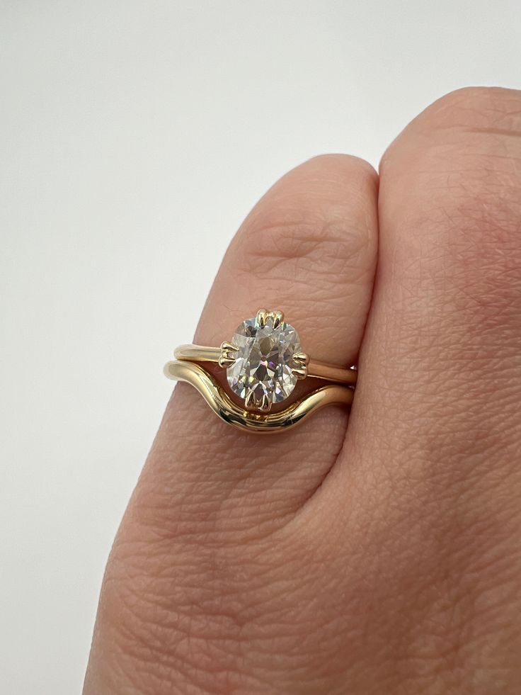 a person's hand holding a gold ring with a diamond