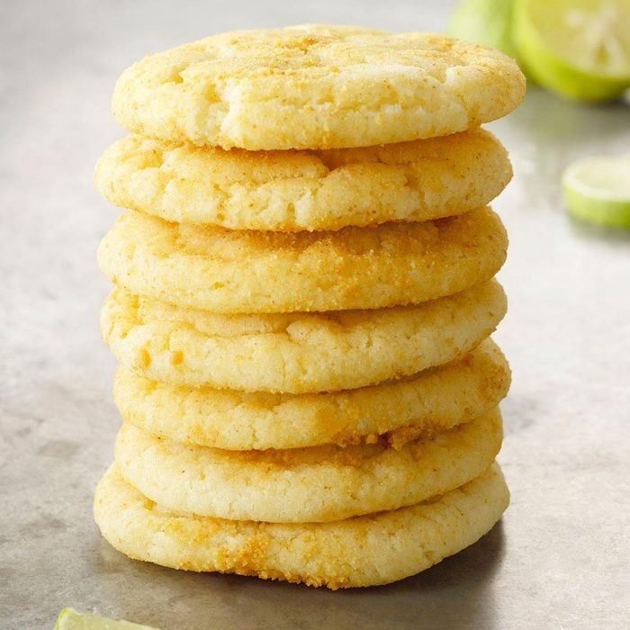 a stack of cookies sitting on top of a counter next to limes and a knife