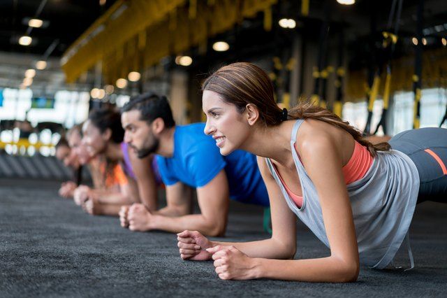 a group of people doing push ups in a gym stock photo