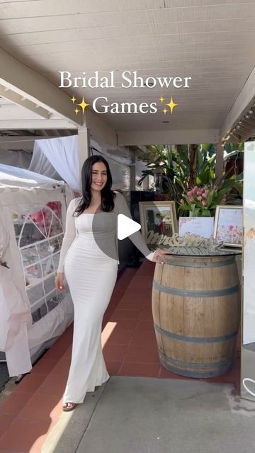 a woman in a white dress standing next to a barrel with pictures on it and the words bridal shower games