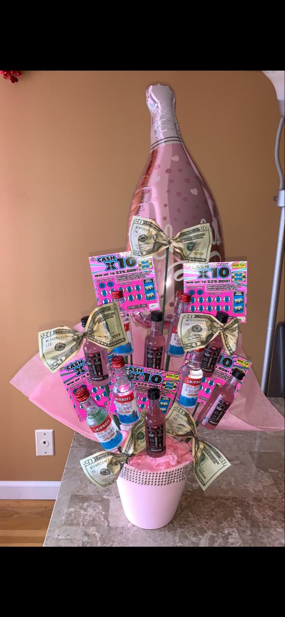 a pink vase filled with money sitting on top of a counter next to a bottle