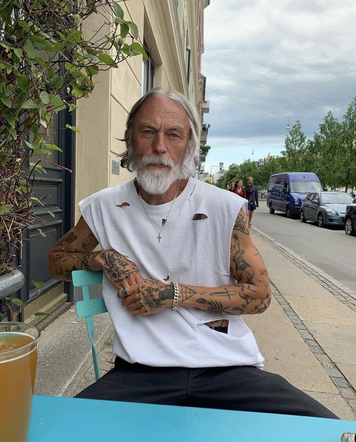 an older man with tattoos sitting at a table