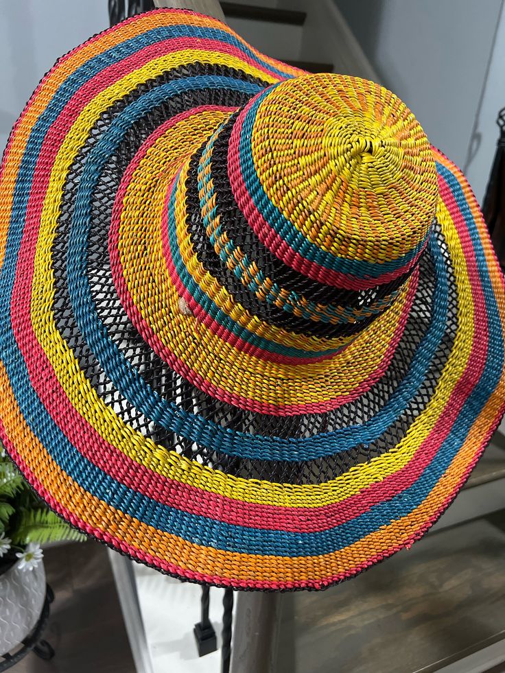 Calm your sunny weather with this airy shade featuring a wide floppy brim. Our traditional hat is hand woven by the best artisans in Ghana. It is made of elephant grass and can reshape to your liking. It comes with an adjustable strap to hold the hat in place. The hat is ideal for your occasions. Wear it to the beach, farmers market for shopping, or a casual day in town. This is also a perfect spring and summer gift to complement your fashion sense. This will make an ideal gift for someone to wear or hang on the wall for decor. It is durable and non-toxic, Size-please refer to the measurements in this description. Material: elephant grass, adjustable leather strap, waterproof Measurements: Hat brim 6"   Head circumference 25"  Dome Height  5" Care Instructions: Your item may arrive pressed Multicolor Fedora Hat In Toquilla Straw, Multicolor Toquilla Straw Fedora Hat, Yellow Wide Brim Straw Hat In Toquilla Straw, Multicolor Toquilla Straw Hat With Curved Brim, Multicolor Toquilla Straw Fedora, Yellow Wide Brim Toquilla Straw Hat, Multicolor Brimmed Hat With Uv Protection, Woven Sun Hat For Summer, Handwoven Summer Hats In Multicolor