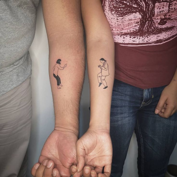 two people holding hands with tattoos on them