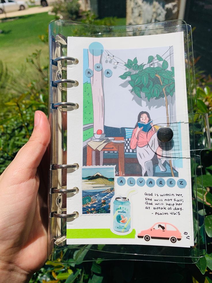 a person holding up a small book with pictures on the pages and writing in it