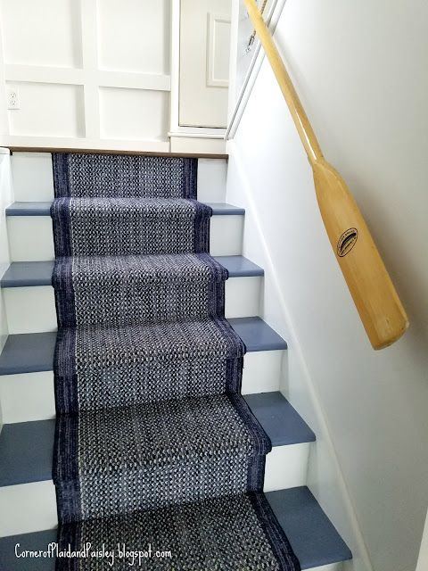 a blue and white stair case with a wooden paddle on the wall next to it