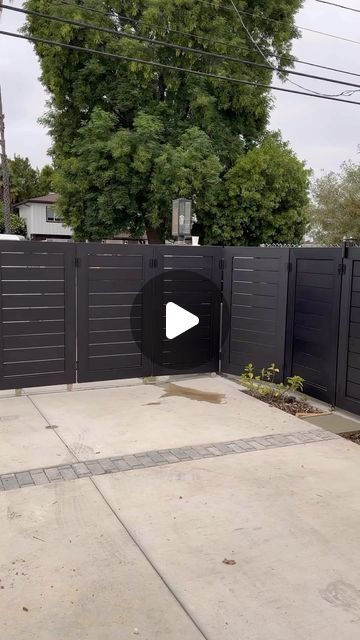 an empty driveway with a black fence and trees in the backgroung area