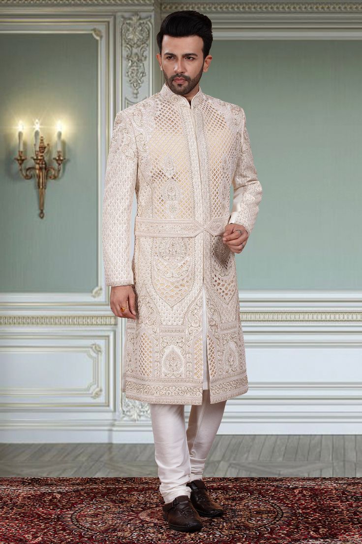 Expertly crafted, this Mens Sherwani- R14-S96 offers a unique and distinguished look for any groom. Adorned with intricate white beads and a stylish belt, this sherwani is sure to stand out. Elevate your wedding attire with this exquisite piece and make a statement on your special day. Elegant Nehru Jacket With Cutdana In Traditional Drape, Elegant Formal Nehru Jacket With Cutdana, Elegant Nehru Jacket With Cutdana Detailing, Elegant Nehru Jacket With Cutdana, Elegant Bandhgala With Cutdana For Reception, Elegant Cutdana Bandhgala For Reception, Formal Off White Kurta With Cutdana, Formal Off-white Kurta With Cutdana, Off White Naqshi Bandhgala