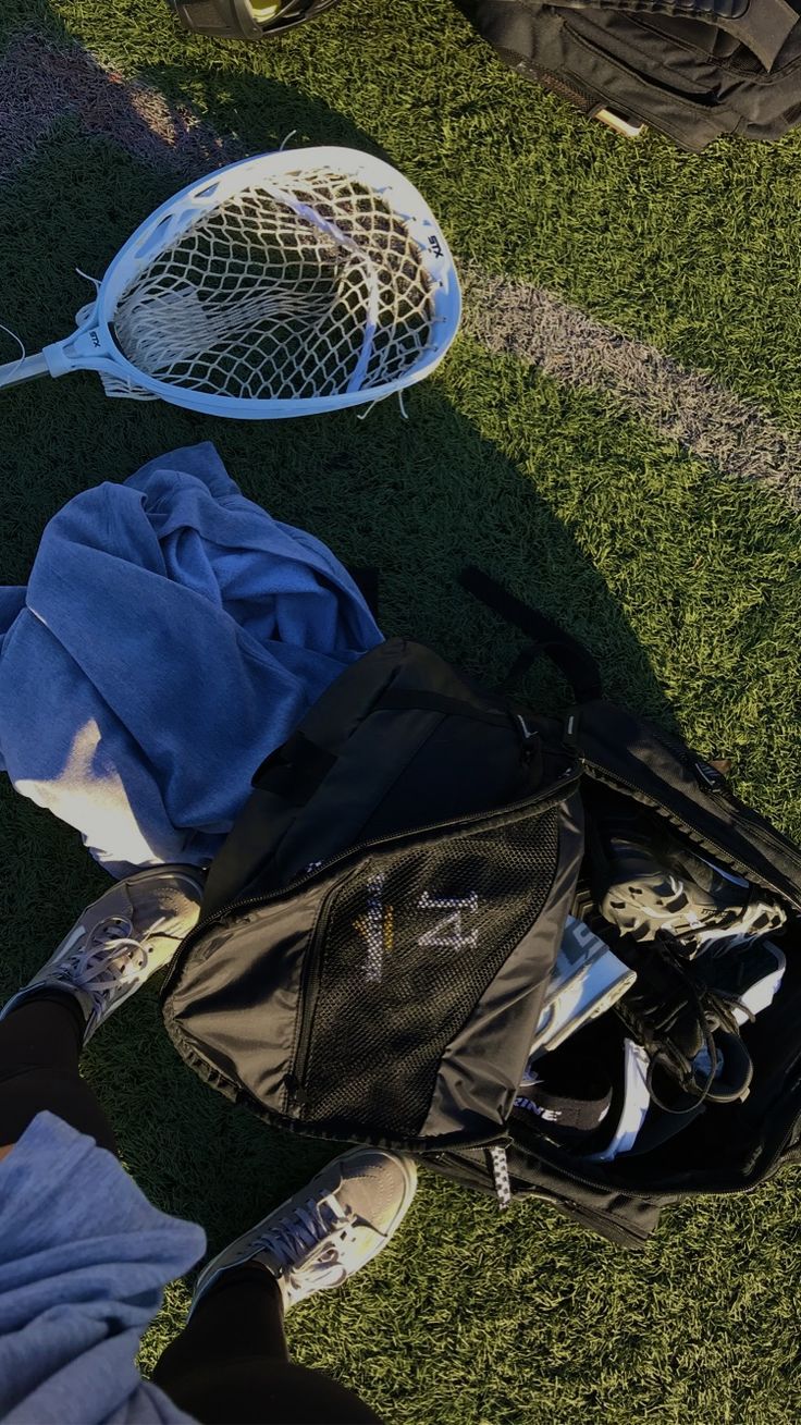 two tennis racquets are laying on the grass next to a backpack and bag