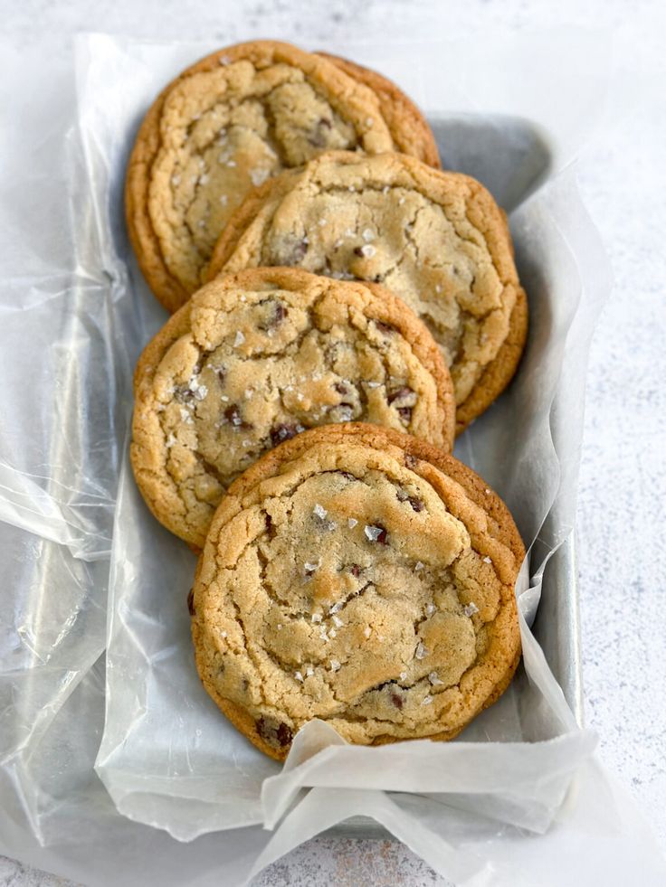 four chocolate chip cookies in a tin on a table