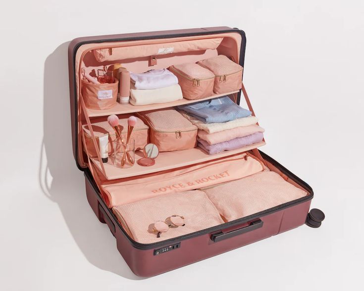 an open suitcase filled with personal items on top of a white surface and in front of it