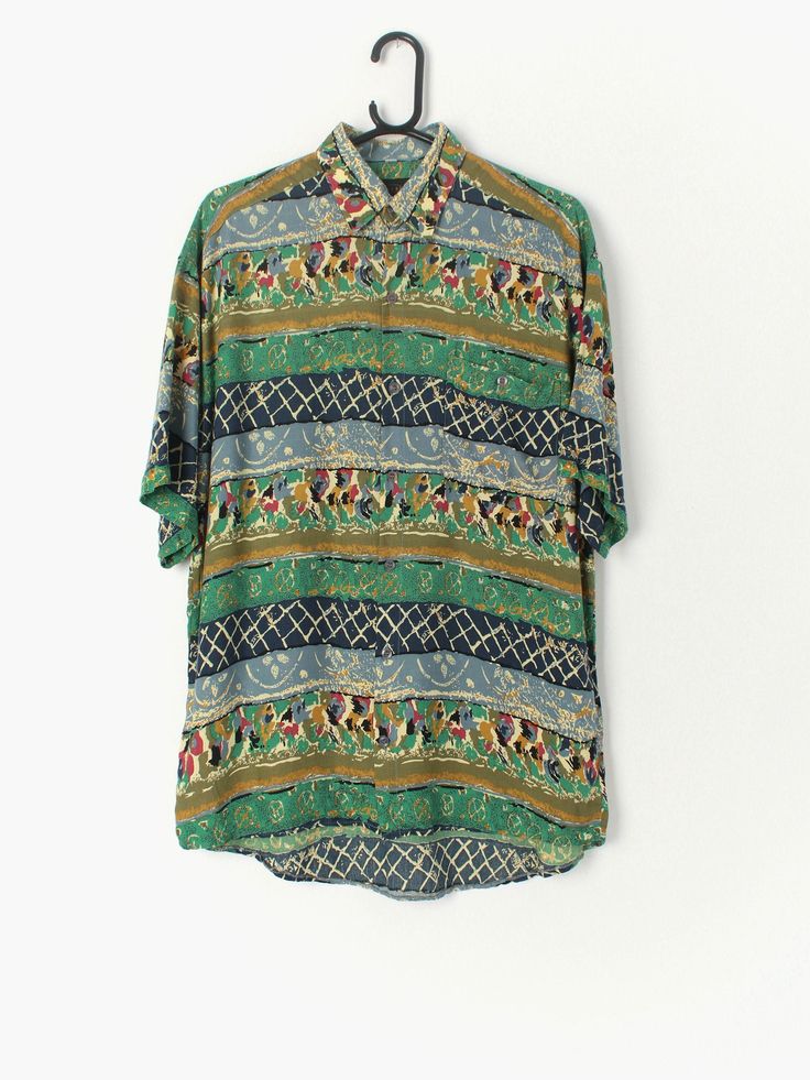 Mens vintage crazy print shirt with stunning pattern in green, mustard yellow, pink and navy. Features one front pocket with button closure. A lovely lightweight fabric with really a really nice arty crazy print. Our recommended size: Medium Label says: M Condition: very good Material: viscose/rayon Measurements in inches: Pit to pit: 22 Shoulders: 21 Front length: 29 Back length: 31.5 Sleeve length: 9.5 https://www.stcyrvintage.co.uk https://www.instagram.com/stcyrvintage https://www.facebook.c Dark Blue Shirt, Abstract Shirt, Fleece Plaid, Vintage Hawaiian Shirts, Vintage Hippie, Wool Vest, Viscose Rayon, Vintage Hawaiian, Mens Vintage