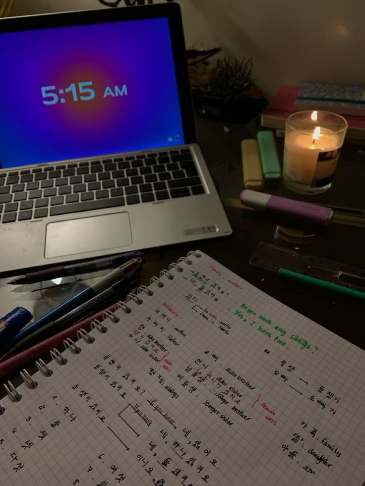 an open laptop computer sitting on top of a desk next to a notebook and pen