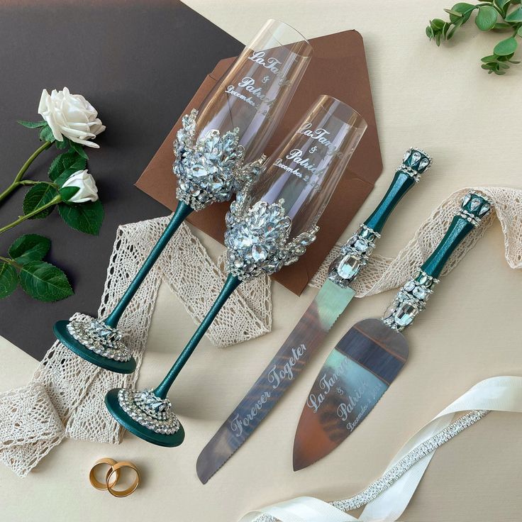 two wine glasses and a knife sitting on top of a table next to some flowers