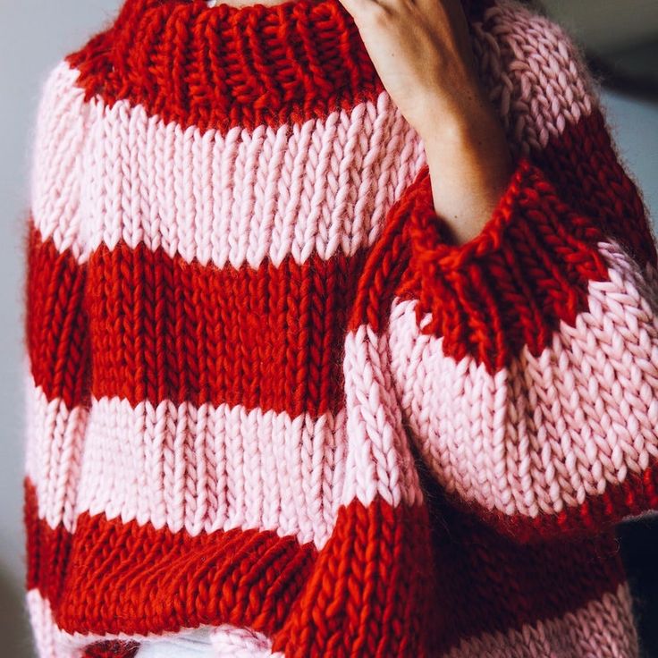 a woman wearing a red and white striped sweater is holding her hand to her face