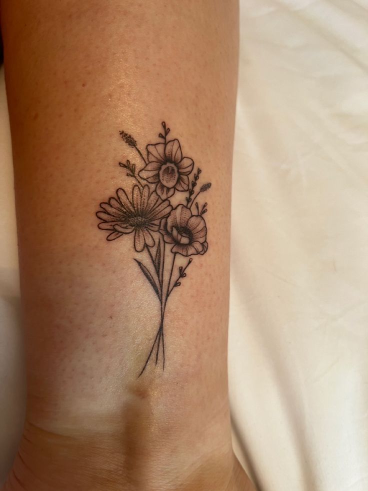 a woman's lower leg with flowers on the bottom and one flower in the middle