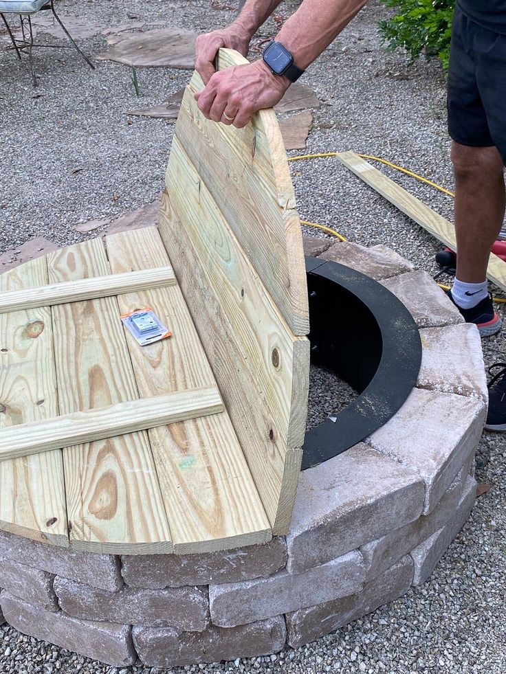 a man is working on an outdoor fire pit made out of pallets and wood