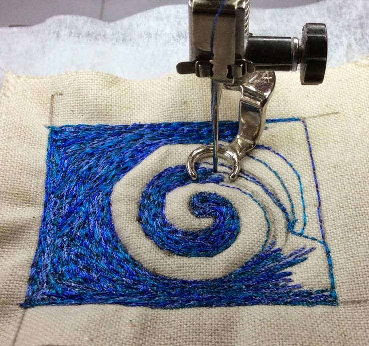 a close up of a sewing machine on a piece of fabric with blue and white thread