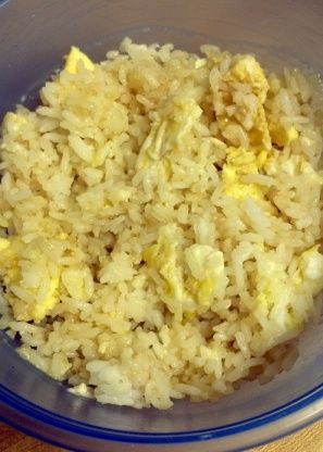 a bowl filled with rice and eggs on top of a wooden table