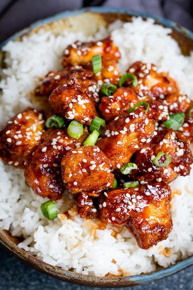 a close up of food on a plate with rice and green onions in sauces