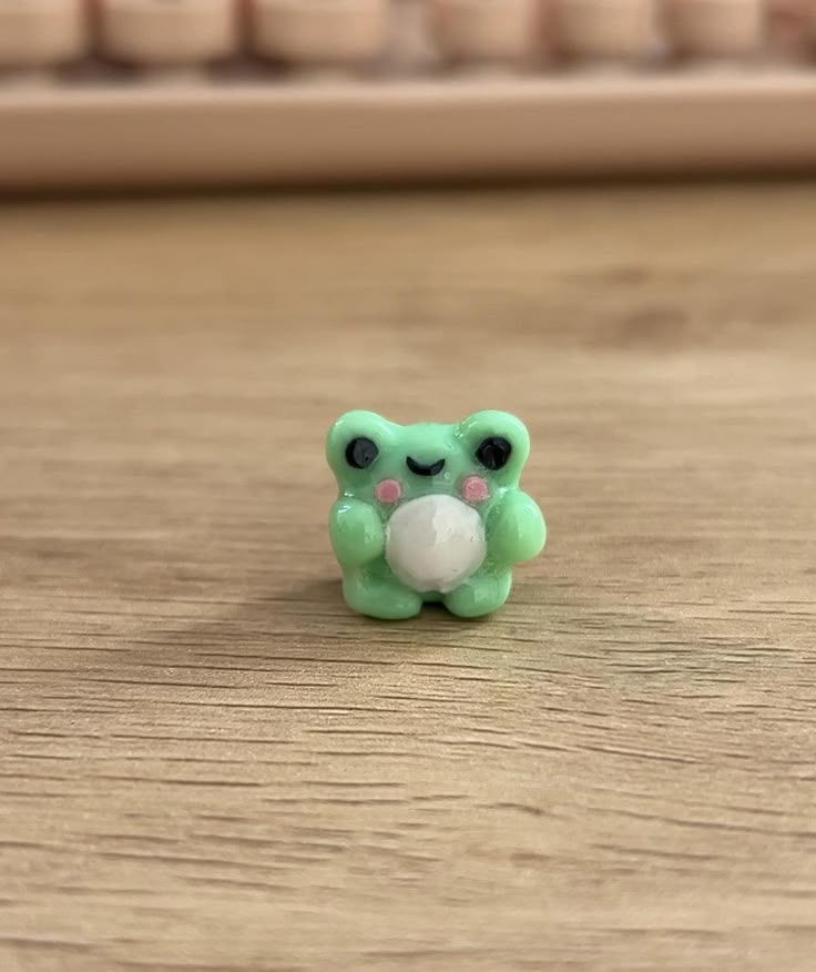 a small green teddy bear sitting on top of a wooden table