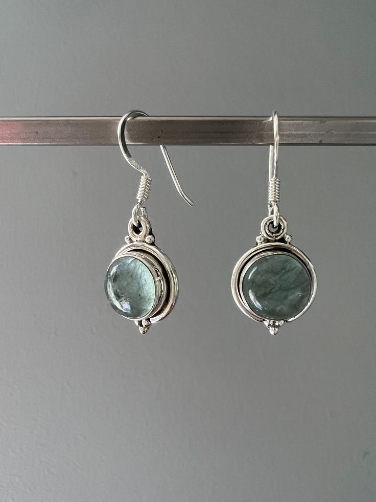 Sterling silver aquamarine dangle earrings . Beautiful Aquamarine stones set in sterling silver. All stones are natural and therefore each one is unique. Aquamarine is a healing stone, a stone of courage used for reducing stress and calming the mind. Promotes self expression and increases sensitivity and highly protective during pregnancy. Boosts the immune system and a great meditation stone. Birthstone of March. Gift box available for purchase. Search GIFTBOX Aquamarine Matching Earrings Jewelry, Aquamarine Round Jewelry With Matching Earrings, Aquamarine Earrings Gift, Silver Aquamarine Gemstone Earrings, Silver Aquamarine Round Earrings, Silver Aquamarine Jewelry Set With Earrings, Silver Blue Topaz Drop Earrings, Silver Aquamarine Dangle Earrings, Dangle Earrings With Green Amethyst Gemstone