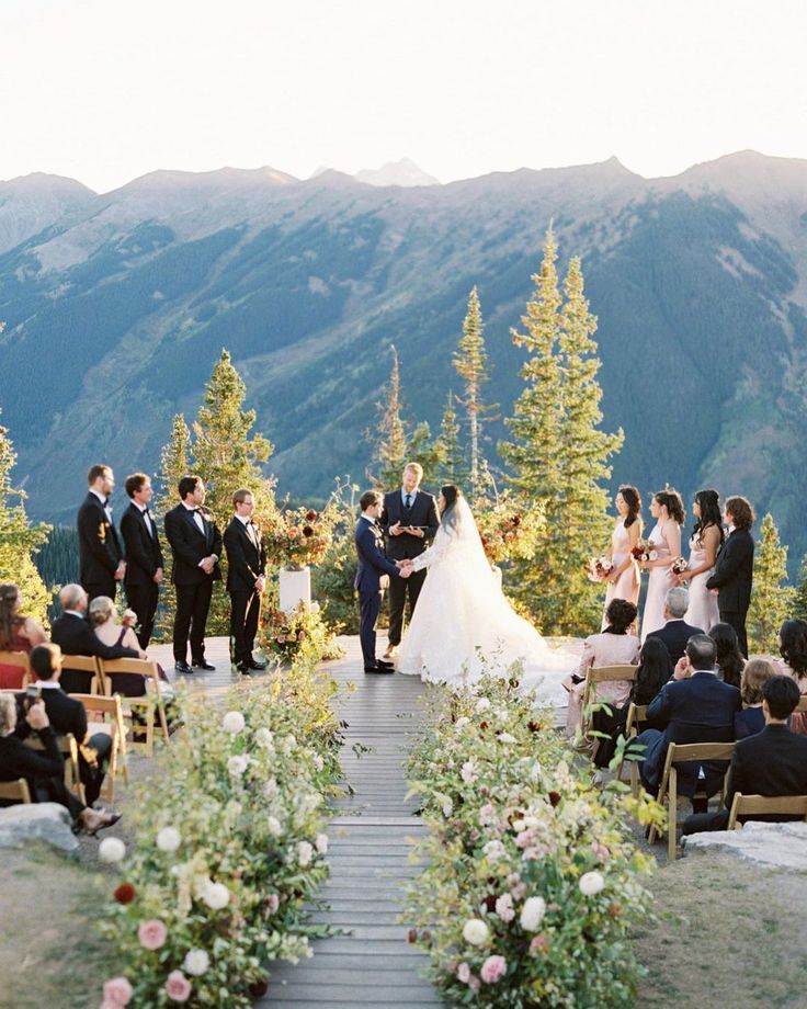 a bride and groom walking down the aisle at their outdoor wedding ceremony with mountains in the background