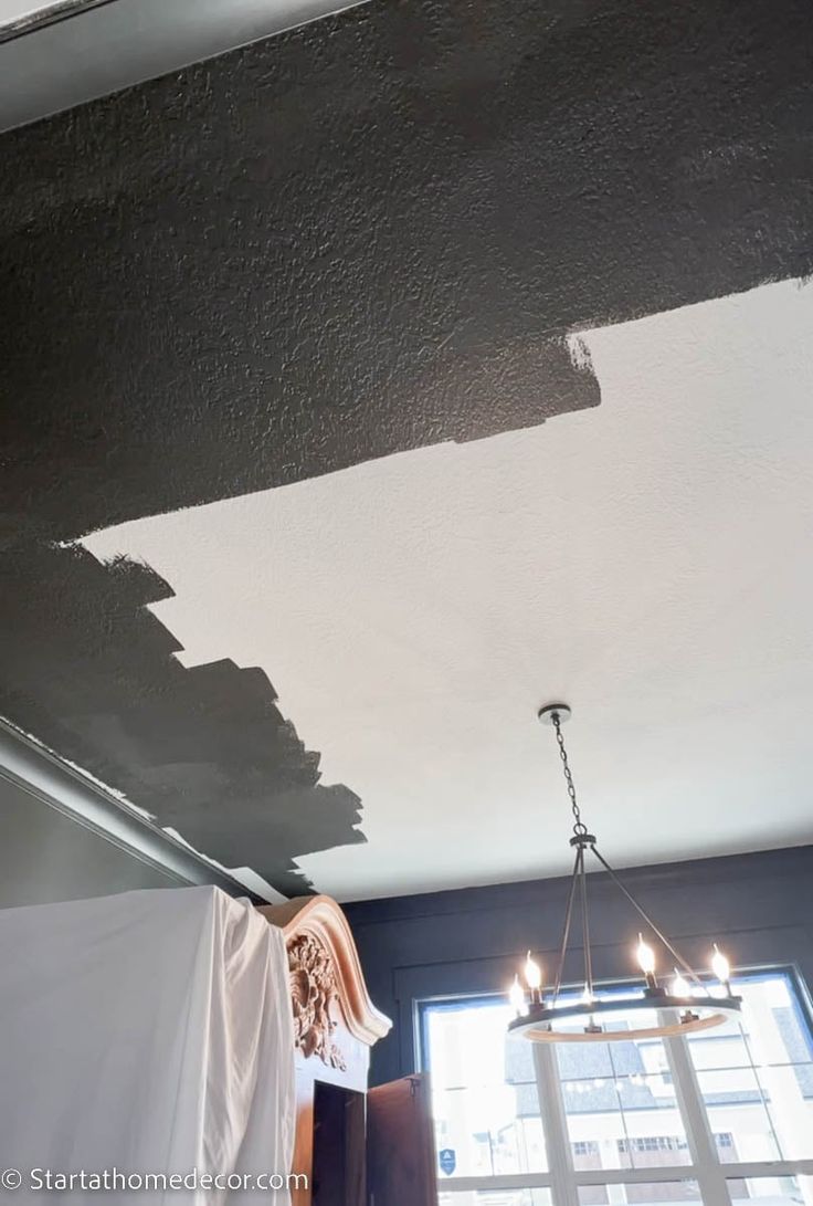 a room that has been painted black with some light on the ceiling and a chandelier hanging from the ceiling