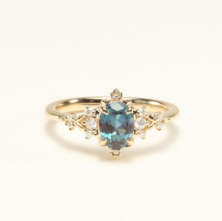 a gold ring with an oval blue stone surrounded by small white diamonds on the side