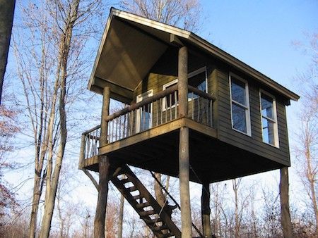 a tree house in the woods with stairs leading up to it's second floor