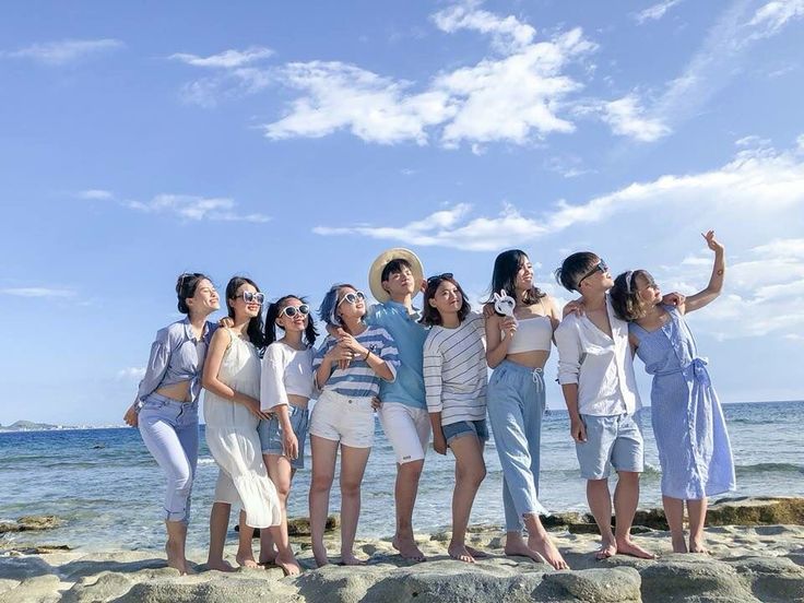 a group of women standing next to each other on top of a sandy beach near the ocean