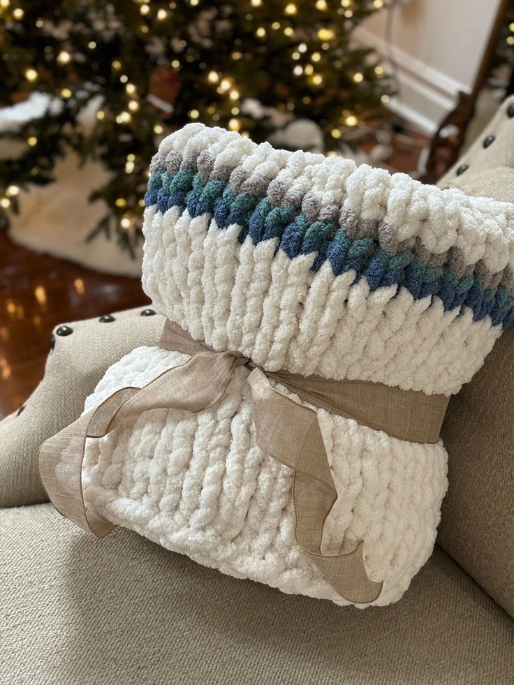 two knitted pillows sitting on top of a couch next to a christmas tree