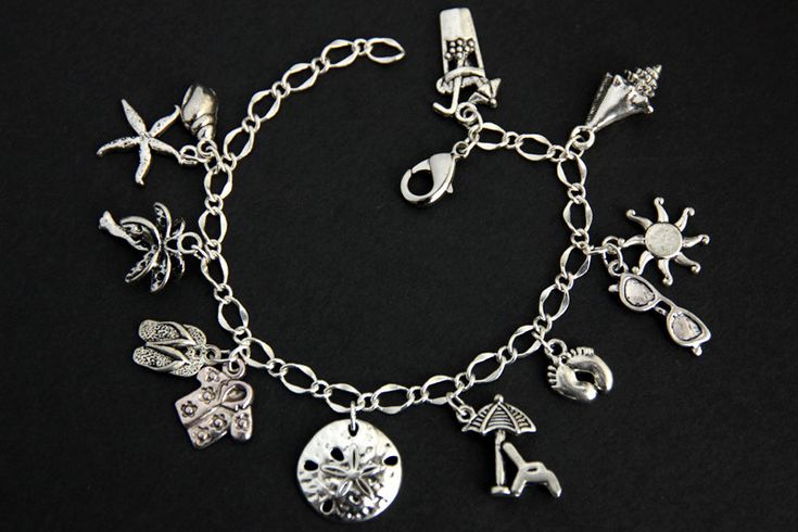 A collection of silver plated beach vacation themed charms have been dispersed around a shimmering silver plated bracelet chain in this handmade charm bracelet. This summer vacation charm bracelet is then completed with a lobster clasp and a 1/2 inch of chain at the end for adjustable sizing. Charms in this bracelet include a tropical drink charm, conch charm, sunglasses charm with sun charm, bare feet charm, beach chair with umbrella charm, sand dollar charm, tropical shirt charm with flipflops Elegant Silver Charm Bracelet For Beach, Beach Metal Bracelets With Charms, Metal Charm Bracelets For Beach, Bohemian Silver Charm Bracelet For Beach, Silver Metal Charm Bracelet For Beach, Beach Chair With Umbrella, Dog Charm Bracelet, Tropical Shirt, Handmade Charm Bracelets