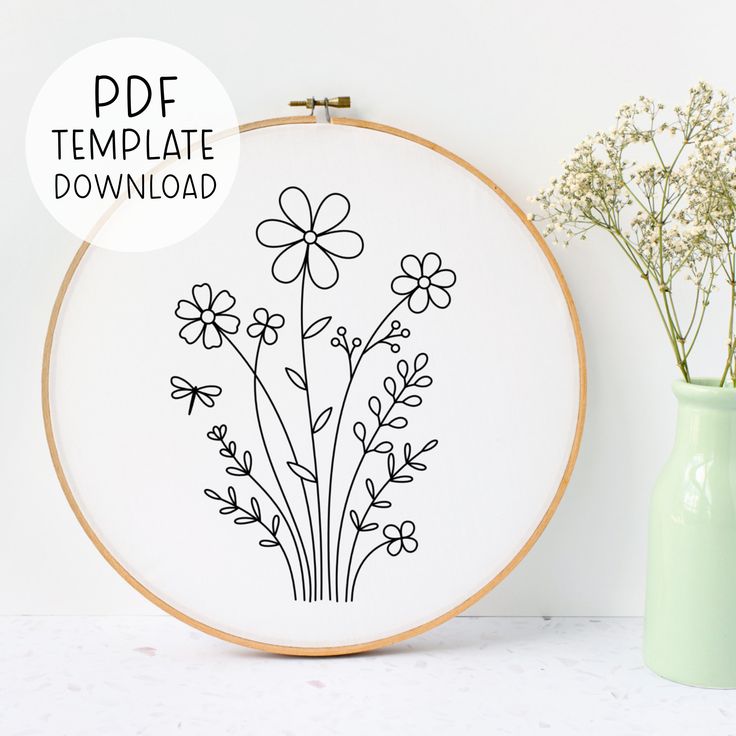 an embroidery pattern with flowers on it next to a green vase filled with baby's breath