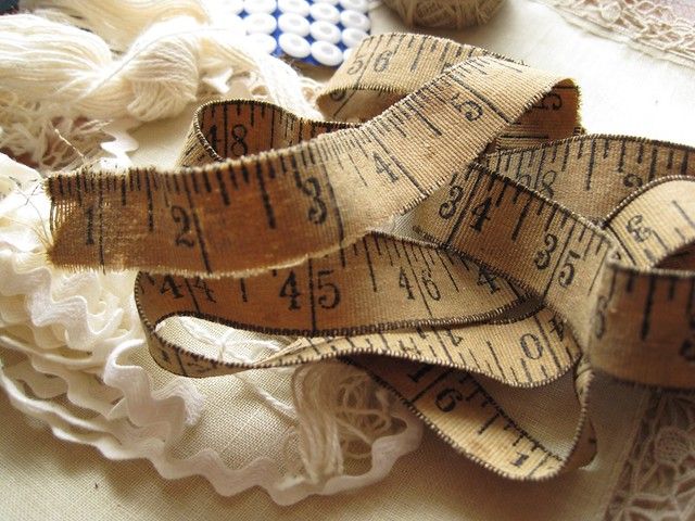 a close up of a measuring tape on a table with doily and other crafting items