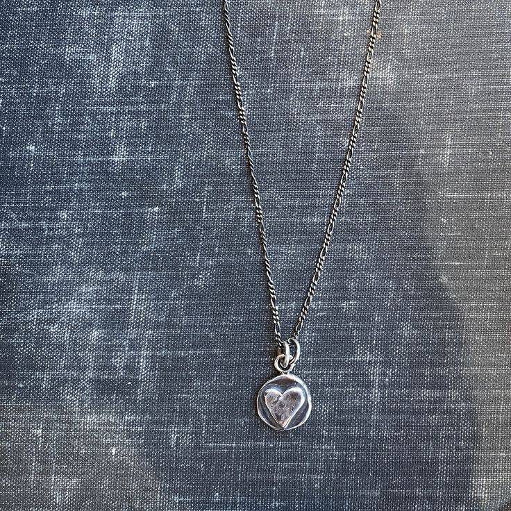 "This nickel-sized solid sterling silver heart pendant is a great way to bring you or a loved-one a virtual hug. The perfect gift. May request up to 3 initials stamped on the back (request in notes). Cast from recycled sterling silver scrap metal. Available in 16\" & 18\" length (make your selection at check out) on an oxidized (antiqued) flat figaro style chain." Silver Necklace With Initial Pendant And Heart Charm, Nickel-free Heart Pendant Necklace For Everyday, Sterling Silver Heart Necklace With Round Pendant, Silver Heart Charm Necklace For Mother's Day, Silver Hand Stamped Heart Necklace For Anniversary, Silver Heart Necklace With Round Pendant For Keepsake, Silver Heart Necklace With Round Pendant For Mother's Day, Silver Open Heart Keepsake Charm Necklace, Silver Open Heart Charm Necklace For Keepsake