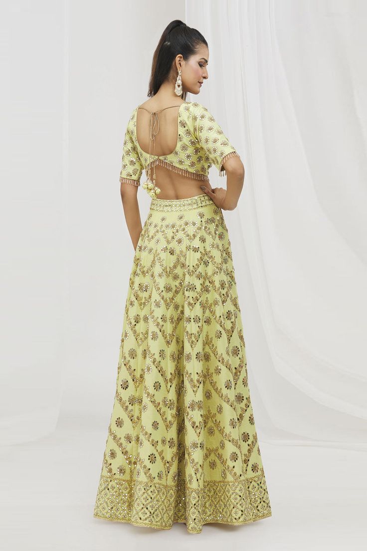 Yellow lehenga featuring delicate gota patti embellished floral motifs in chevron pattern highlighted with mirrorwork, along with attached can can. Comes with matching crystal tasselled padded blouse and embroidered dupatta.
Components: 3
Pattern: Embroidered
Type Of Work: Gota Patti, Mirrorwork
Neckline: Sweetheart
Sleeve Type: Half
Fabric: Dupion Silk
Color: Yellow
Other Details: 
Back tasselled tie detail
Attached lining
Blouse back button closure
Lehenga side tassel drawstring closure
Length Semi-stitched Sets For Reception And Festivals, Raw Silk Resham Embroidered Sets For Reception, Embroidered Pista Green Palazzo Set For Wedding, Embellished Raw Silk Sets For Wedding, Floor-length Wedding Set With Resham Embroidery, Floor-length Sets With Resham Embroidery For Festive Occasions, Embellished Raw Silk Set For Reception, Floor-length Festive Sets With Resham Embroidery, Festive Floor-length Sets With Resham Embroidery