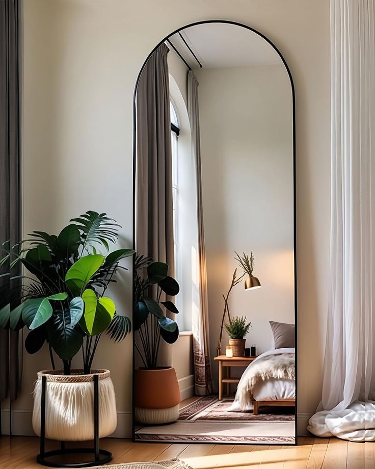 a mirror sitting on top of a wooden floor next to a potted plant