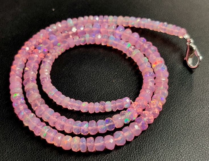 three strands of pink opalite beads on a black surface with a silver clasp