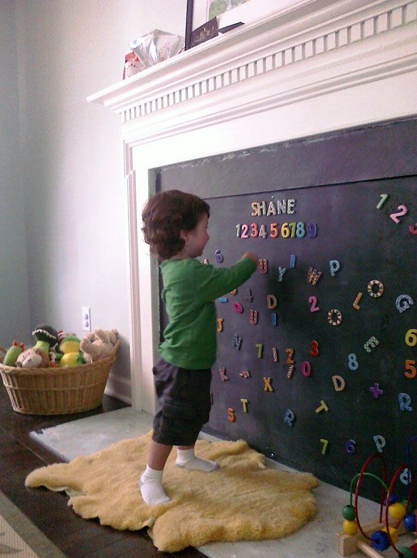 a little boy writing on a blackboard in the living room