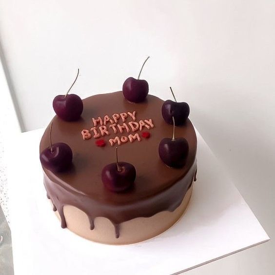 a birthday cake with chocolate frosting and cherries on the top that says happy birthday mom