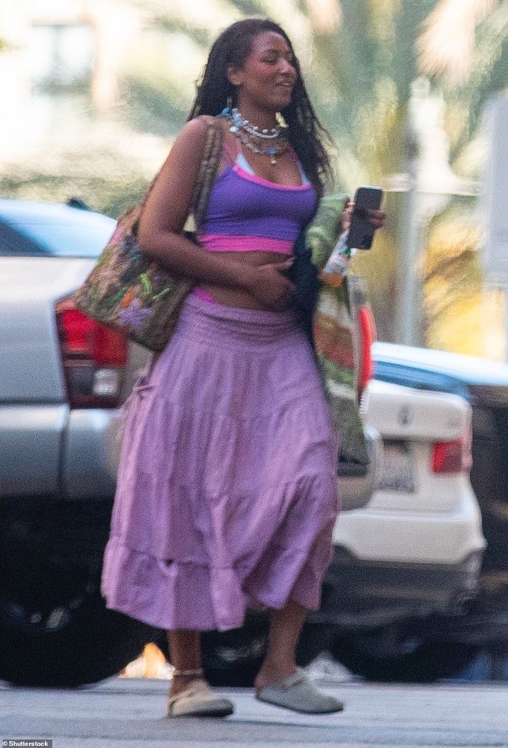 a woman in a purple dress is walking down the street with her hand on her hip